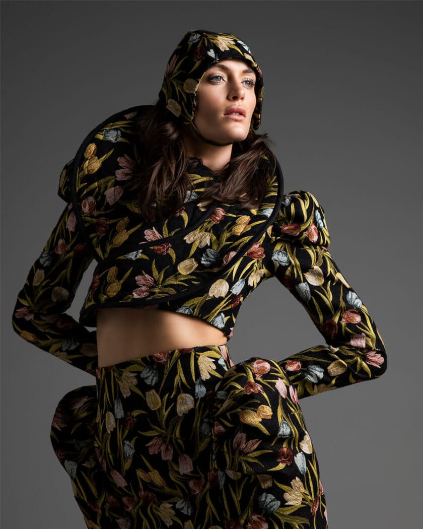 Person wearing a floral-patterned, padded outfit with a matching hood, looking to the side against a plain background.