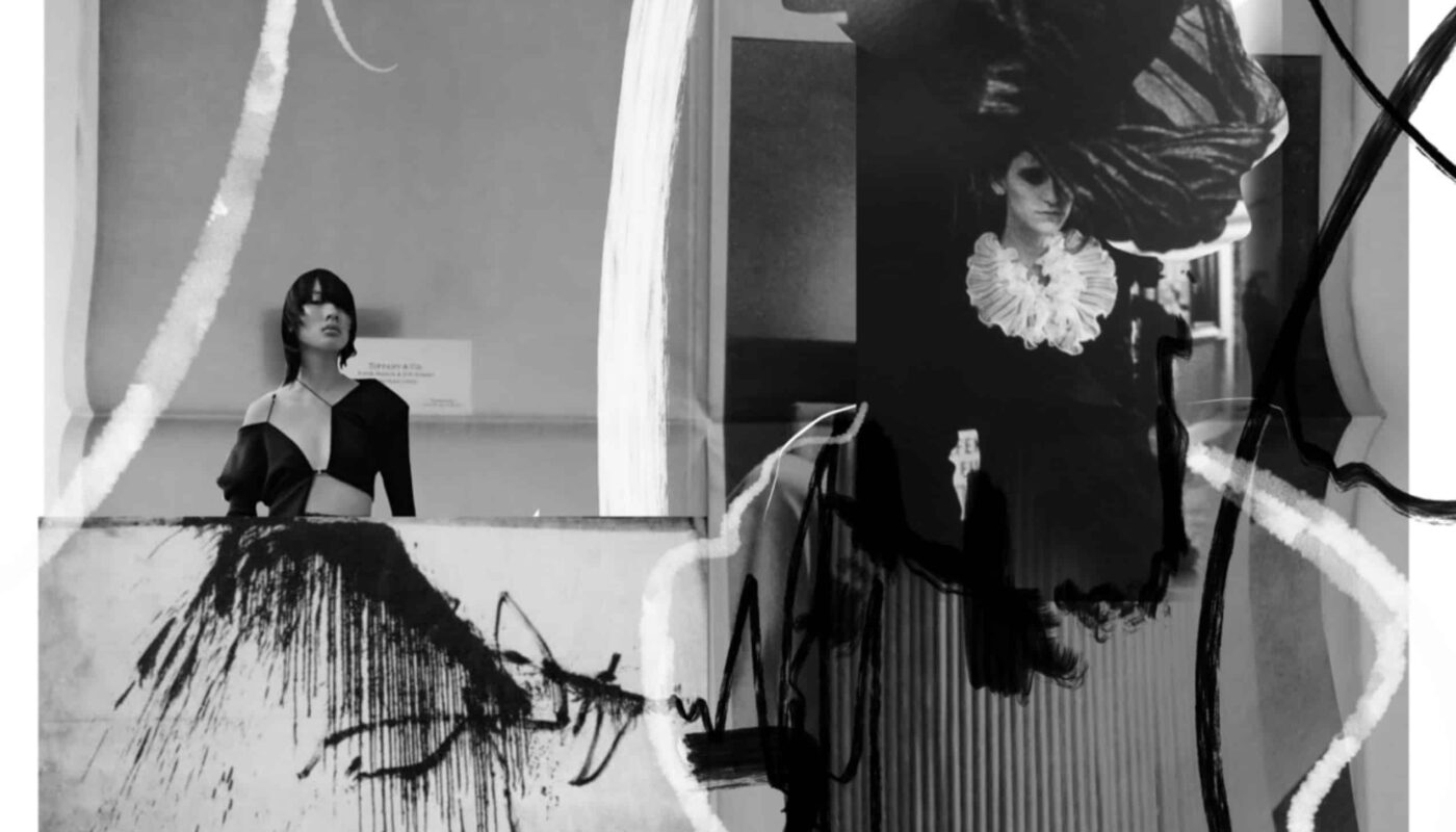 Two women in artistic black-and-white attire, with brush stroke overlays, stand in a museum-like setting. One leans on a counter with an abstract painting, the other wears an elaborate black hat.