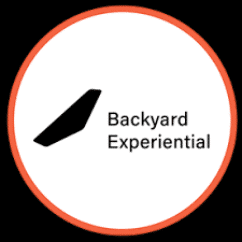 Logo with black geometric shape and text "Backyard Experiential" inside a red-bordered circle on a white background.