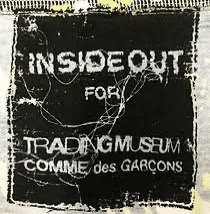 A distressed black label with text "INSIDE OUT FOR TRADING MUSEUM COMME des GARCONS.