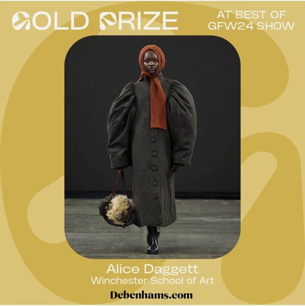 A model in an oversized dark coat and orange headscarf walks on a runway. Text reads "Gold Prize at Best of GFW24 Show" and "Alice Daggett, Winchester School of Art.