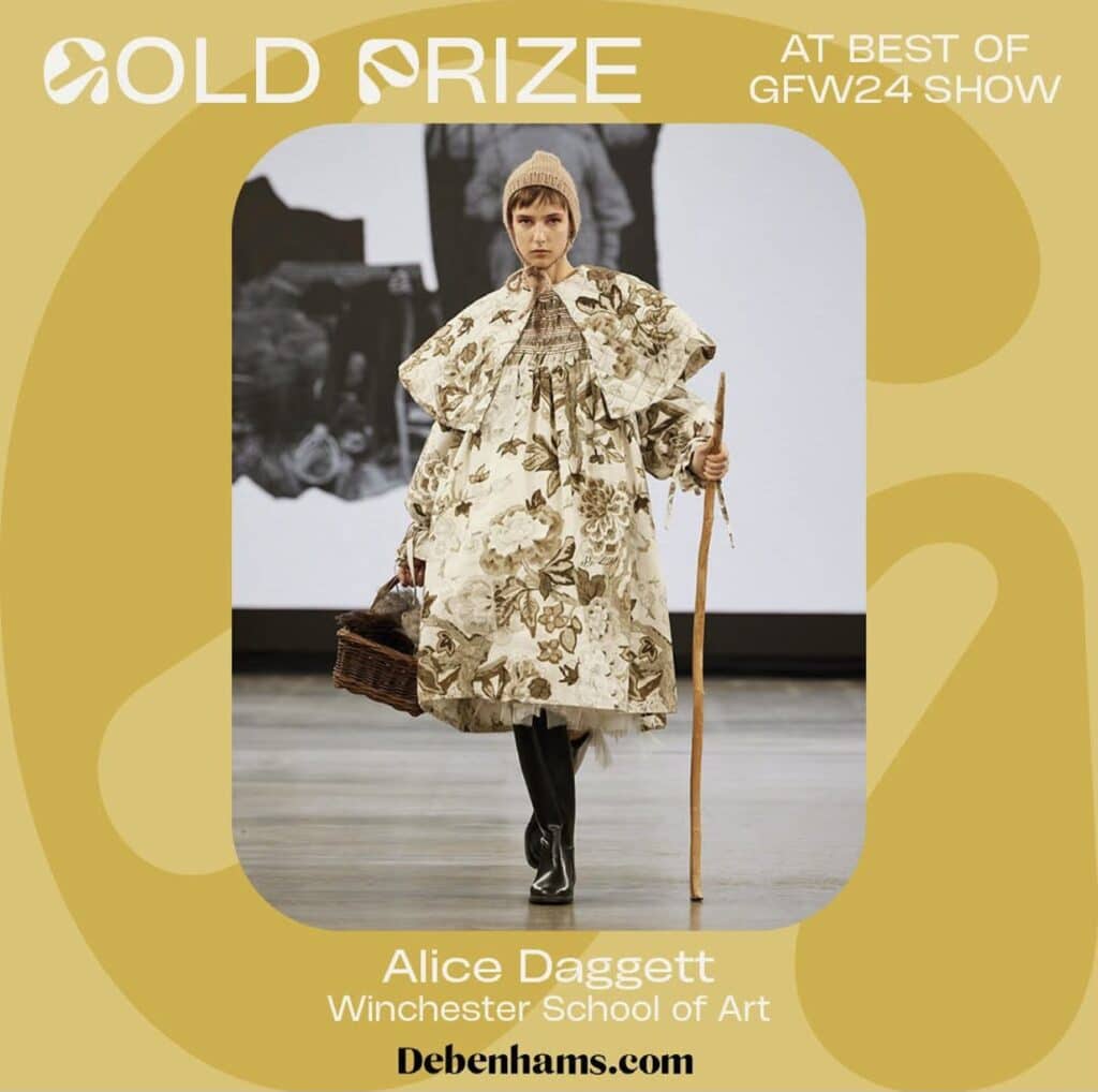 Model in floral outfit and hat, holding a basket and pole, walks runway. Gold Prize at GFW24 Show. Text: Alice Daggett, Winchester School of Art. Debenhams logo in corner.
